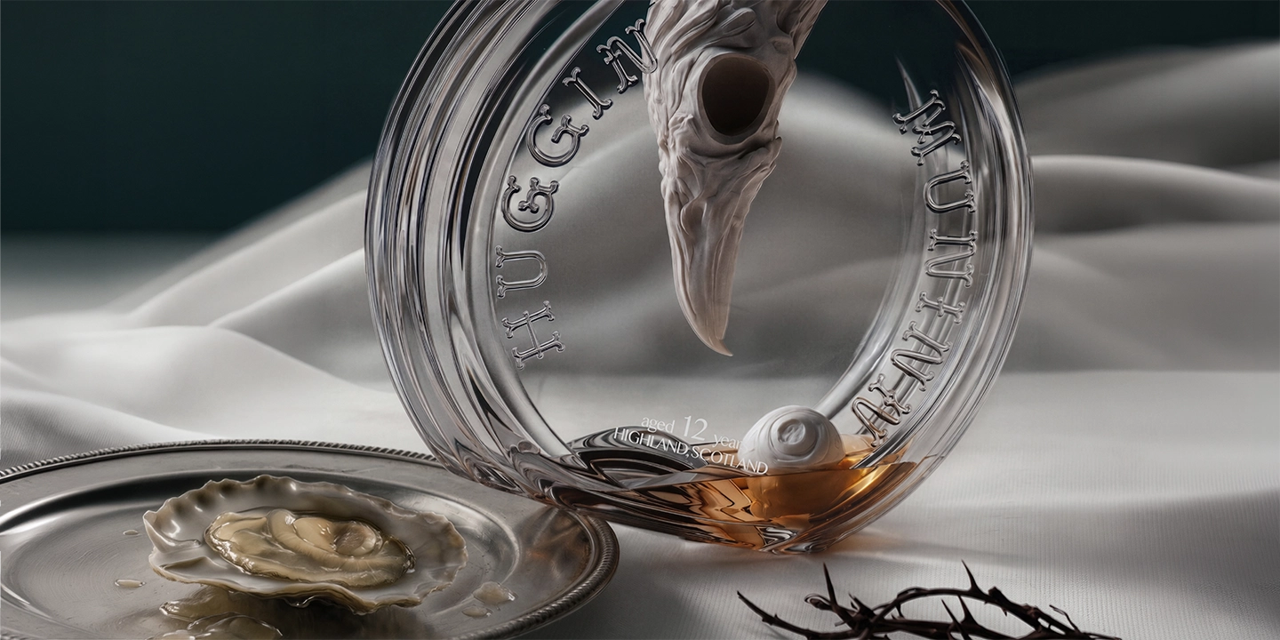 Award-winning creative packaging design for Huginn & Muninn whisky by DEEEZ Design & Creativity Ltd, showcasing a custom sculpted raven bottle closure trapped in the neck, set within an art-historical Scandinavian still-life composition.
